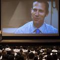Crowd watches a presentation on a large projector screen