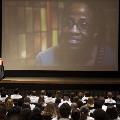 Crowd watches a presentation on a large projector screen