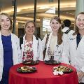 Four students in white coats pose for a photo
